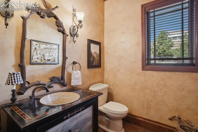 half bathroom featuring tile patterned flooring, baseboards, vanity, and toilet