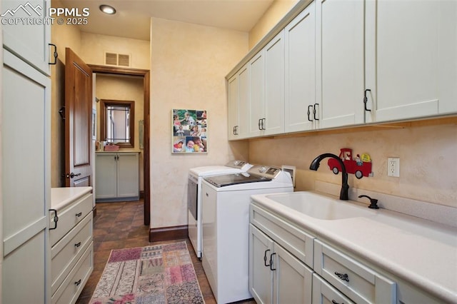 washroom with cabinet space, visible vents, a sink, and separate washer and dryer