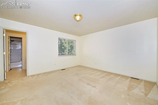 spare room featuring light colored carpet and visible vents