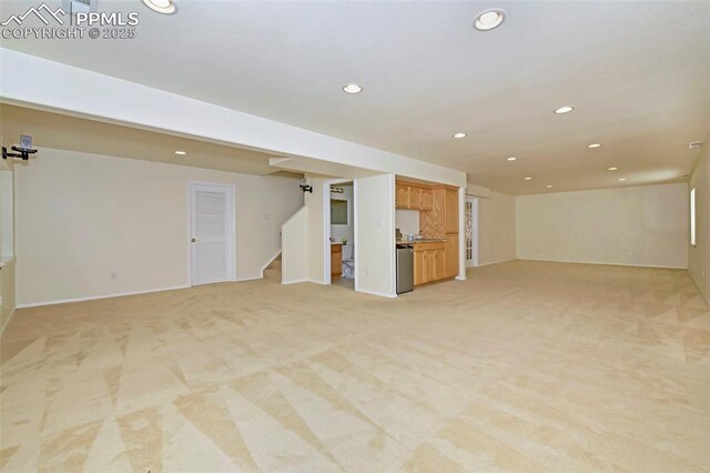 unfurnished living room featuring recessed lighting, light colored carpet, and stairs