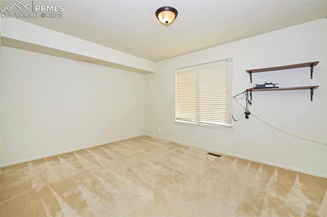 spare room featuring baseboards, visible vents, and light carpet