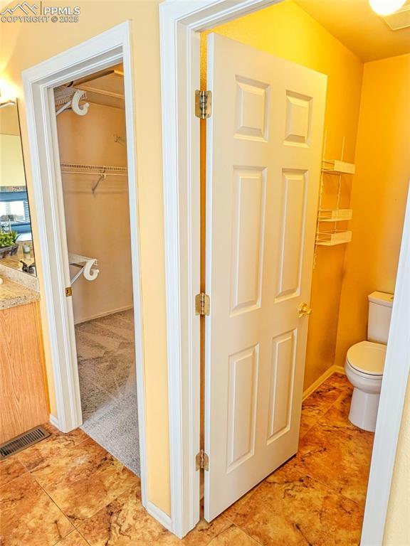 bathroom featuring vanity, toilet, baseboards, and visible vents