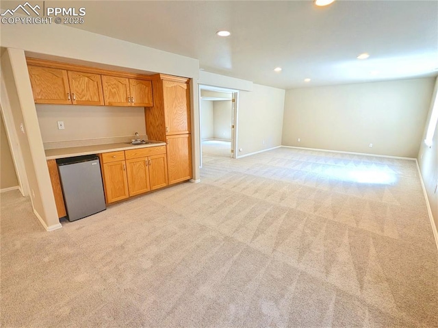 kitchen featuring brown cabinetry, recessed lighting, light countertops, light carpet, and dishwasher