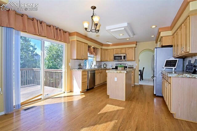 kitchen with light wood finished floors, visible vents, light brown cabinets, a center island, and appliances with stainless steel finishes