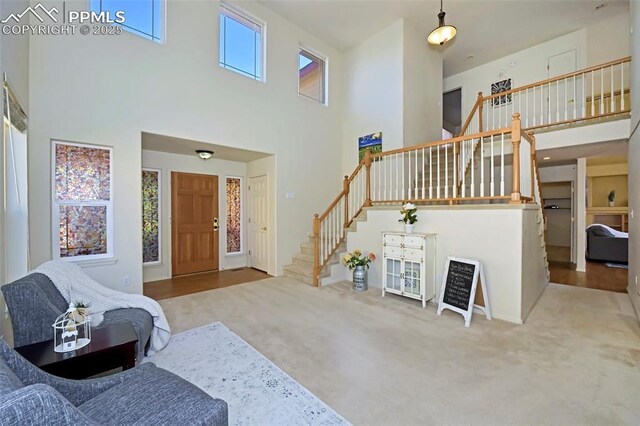 carpeted foyer featuring a towering ceiling and stairs