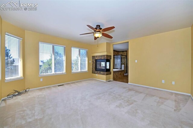 unfurnished living room with ceiling fan, carpet flooring, baseboards, and a tile fireplace