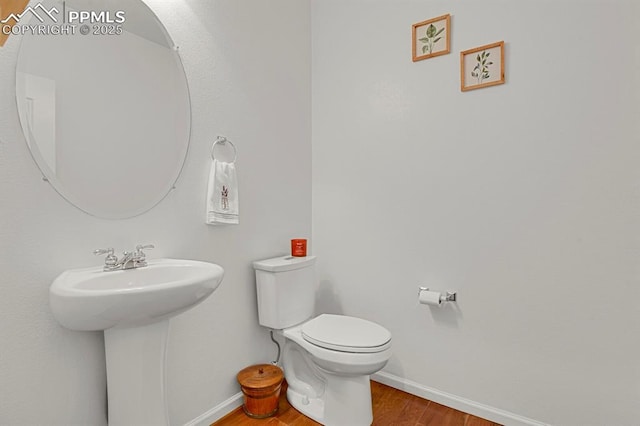 bathroom featuring a sink, toilet, baseboards, and wood finished floors