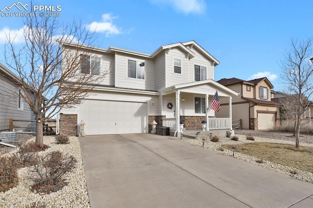 traditional home featuring stone siding, a porch, an attached garage, and concrete driveway