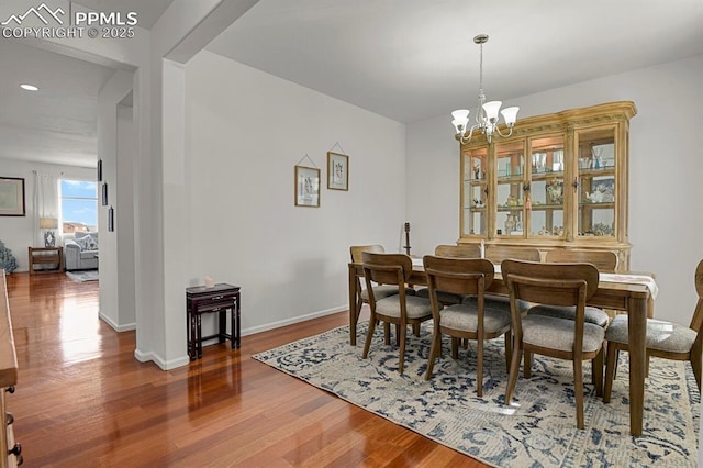 dining space with recessed lighting, wood finished floors, baseboards, and a chandelier