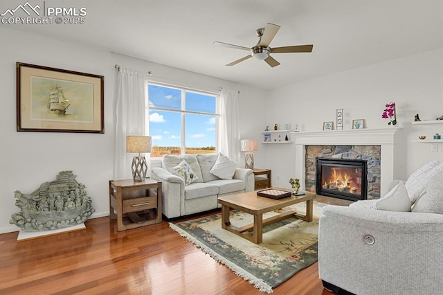 living room featuring a ceiling fan, wood finished floors, and a fireplace