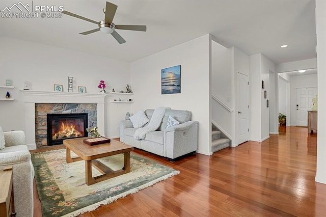 living room featuring stairway, a ceiling fan, wood finished floors, baseboards, and a fireplace