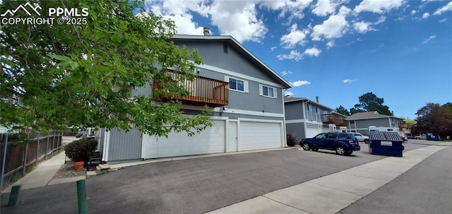 view of front facade featuring a garage, fence, and a balcony