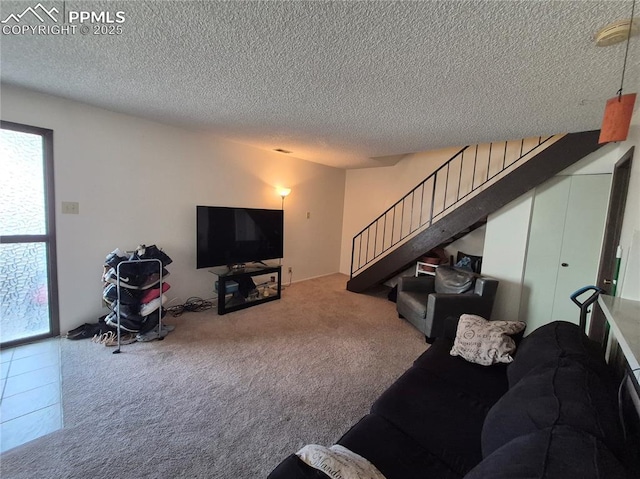 carpeted living area with a textured ceiling and stairs