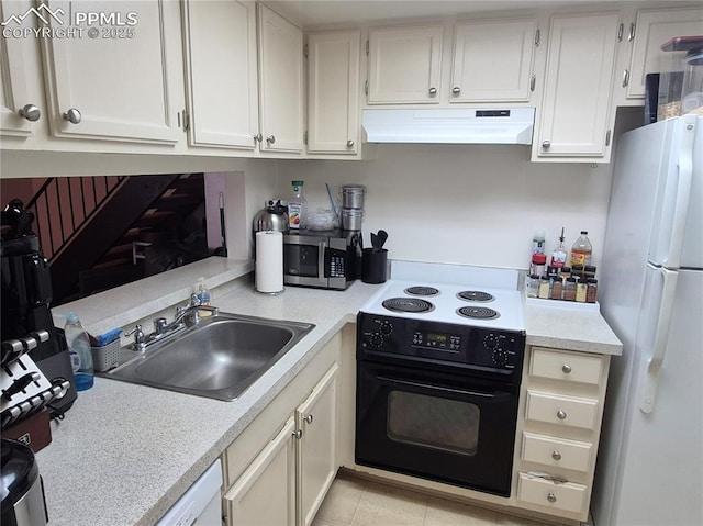 kitchen featuring under cabinet range hood, electric range, a sink, freestanding refrigerator, and stainless steel microwave