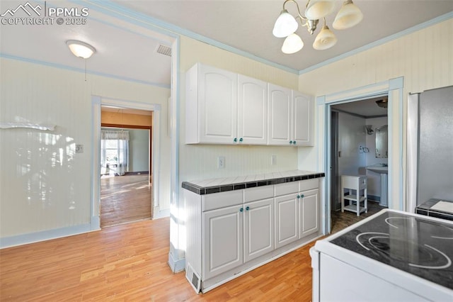 kitchen featuring light wood-style flooring, white electric range, visible vents, white cabinetry, and ornamental molding