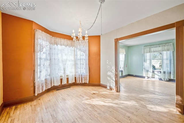 unfurnished dining area featuring a chandelier, wood-type flooring, visible vents, and baseboards