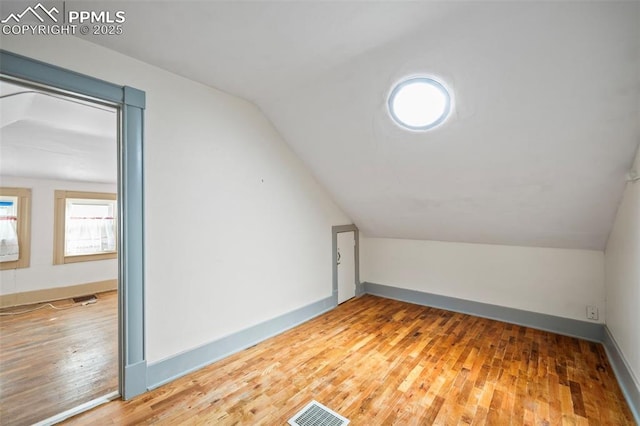 bonus room featuring lofted ceiling, wood-type flooring, visible vents, and baseboards