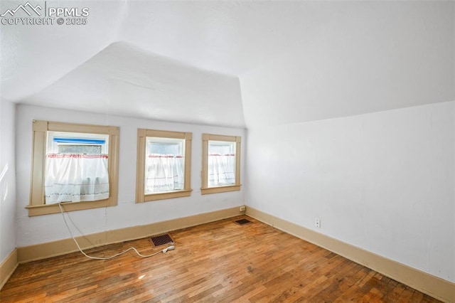 bonus room with lofted ceiling, wood-type flooring, visible vents, and a healthy amount of sunlight