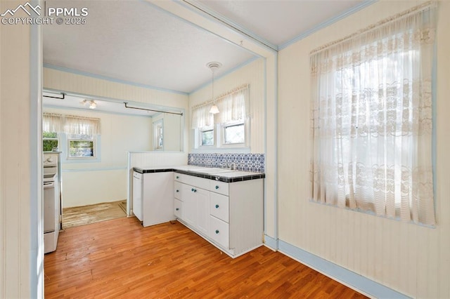 kitchen with tile countertops, light wood finished floors, white cabinets, and crown molding