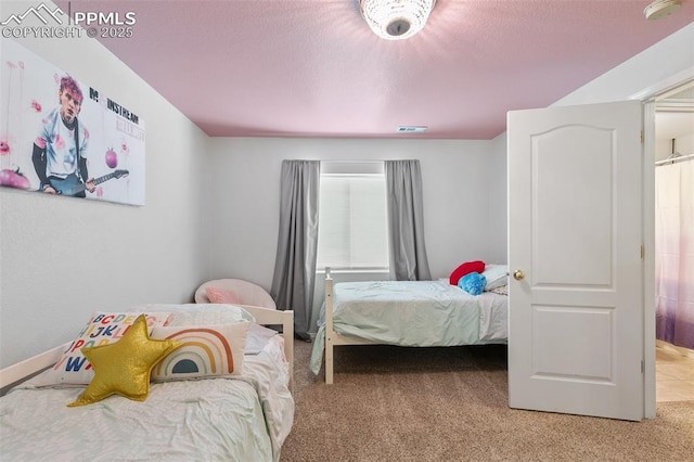 bedroom featuring light carpet, visible vents, and a textured ceiling