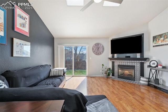 living area featuring baseboards, a tiled fireplace, and wood finished floors