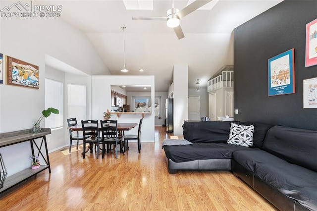 living area with high vaulted ceiling, baseboards, ceiling fan, and light wood finished floors