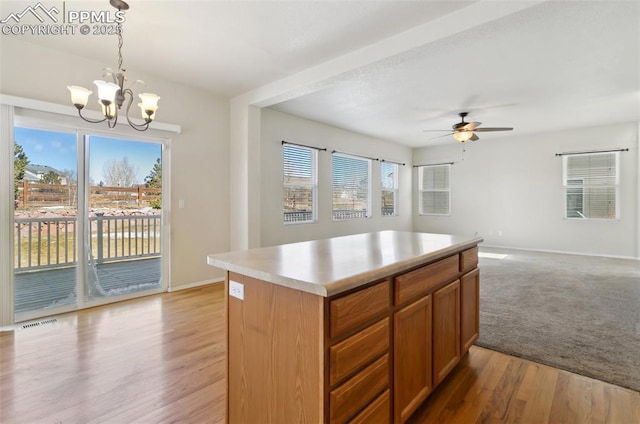 kitchen featuring pendant lighting, light countertops, a kitchen island, and open floor plan