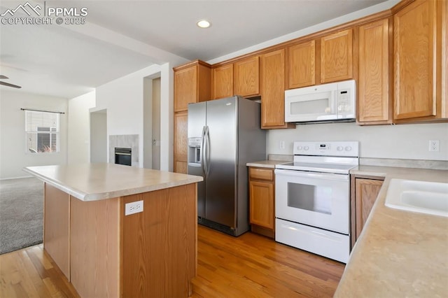 kitchen with white appliances, light wood-style flooring, open floor plan, a center island, and light countertops