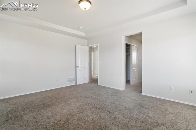 unfurnished bedroom with baseboards, visible vents, a walk in closet, and carpet flooring