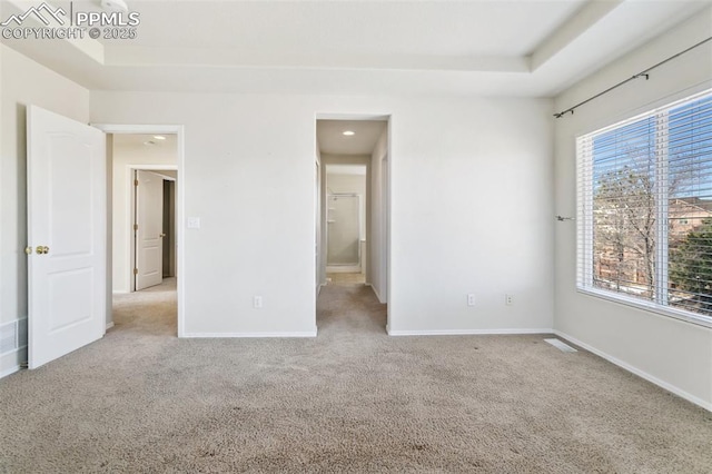 unfurnished bedroom featuring a raised ceiling, carpet flooring, and baseboards