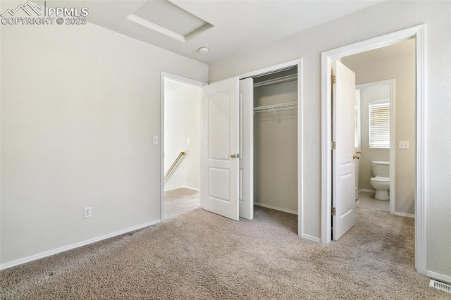 unfurnished bedroom featuring attic access, a closet, carpet floors, and baseboards