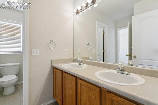 bathroom featuring double vanity, a sink, and toilet