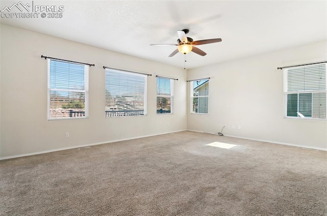 carpeted spare room featuring a ceiling fan and baseboards