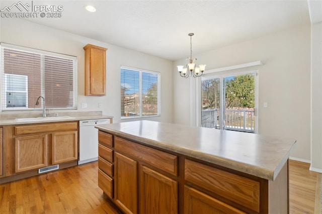 kitchen with light wood-type flooring, visible vents, white dishwasher, and a sink