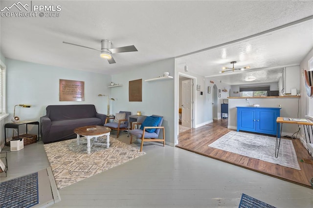 living area with wood-type flooring, a textured ceiling, baseboards, and a ceiling fan