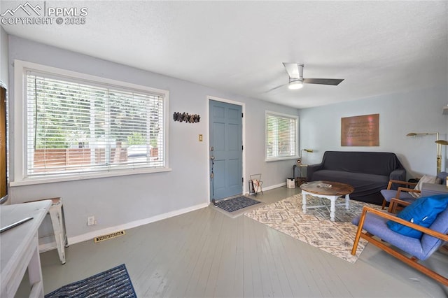 living area with baseboards, visible vents, ceiling fan, hardwood / wood-style floors, and a textured ceiling