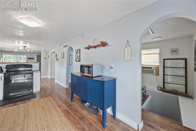 kitchen with arched walkways, a textured ceiling, blue cabinets, electric range, and stainless steel microwave