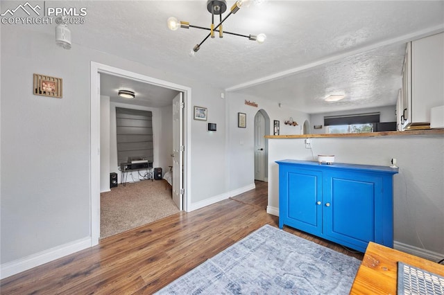 bathroom with a textured ceiling, a chandelier, wood finished floors, and baseboards