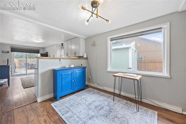 kitchen featuring a textured ceiling, blue cabinetry, wood finished floors, and baseboards