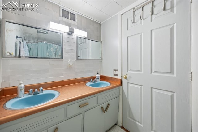 bathroom with double vanity, tasteful backsplash, a sink, and visible vents