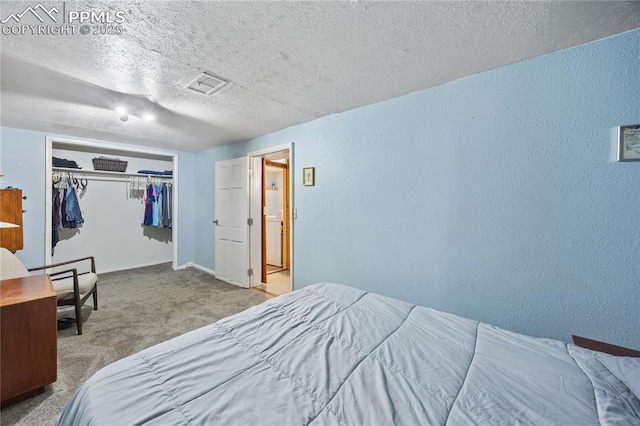 carpeted bedroom with a closet, visible vents, a textured wall, a textured ceiling, and baseboards