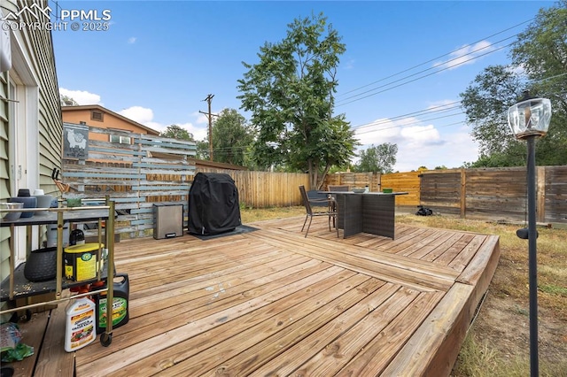 wooden deck featuring outdoor dining area, a fenced backyard, and a grill