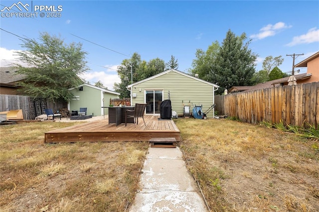 back of house with a deck, a lawn, and fence