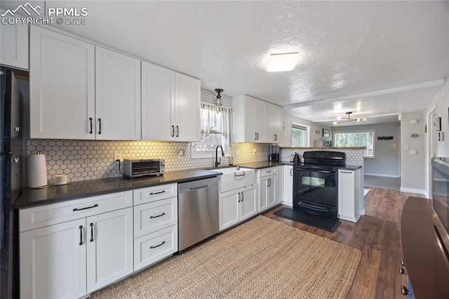 kitchen featuring dark countertops, black appliances, a peninsula, and a sink