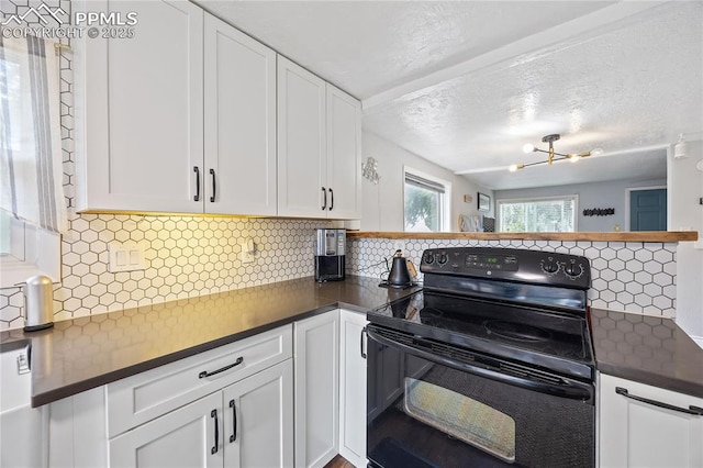 kitchen featuring black range with electric stovetop, dark countertops, white cabinetry, and decorative backsplash