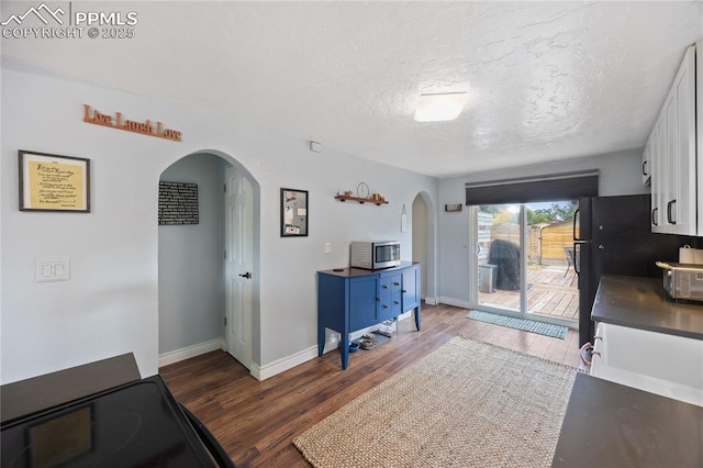 interior space with a textured ceiling, arched walkways, and wood finished floors