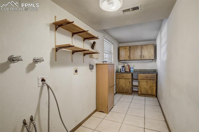 interior space with light tile patterned floors, open shelves, brown cabinetry, and visible vents