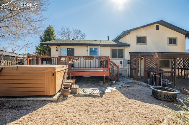 back of property featuring a hot tub, a wooden deck, and stucco siding