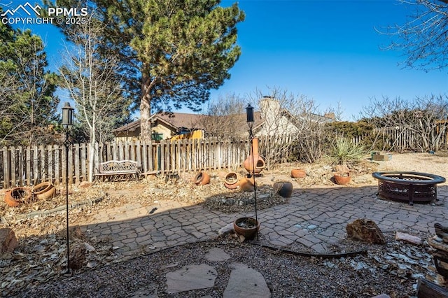 view of yard featuring a fire pit, a patio area, and fence