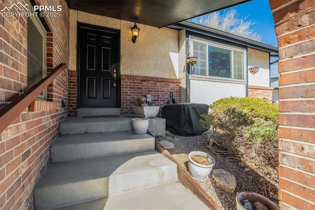 doorway to property featuring brick siding and stucco siding